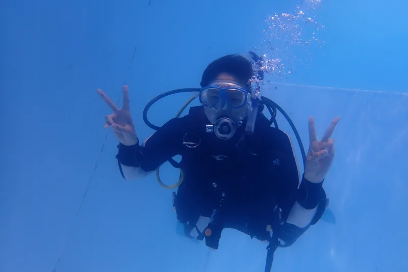 三浦の青い海の中でピースするダイバー