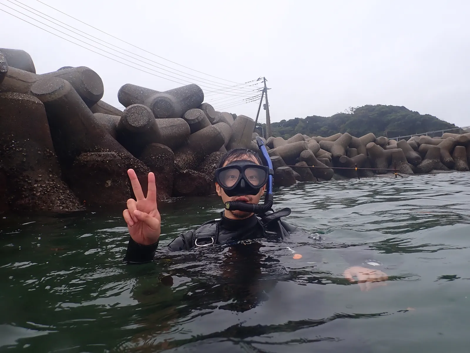 三浦の浅い海で、マスクとスノーケルを着けてピースサインをするダイバー