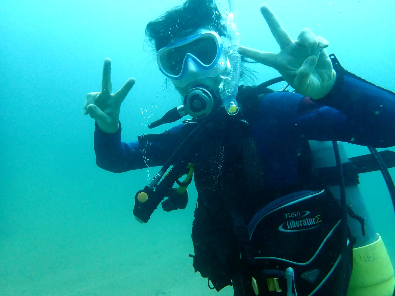 三浦の海の中で、両手でピースサインをするダイバー
