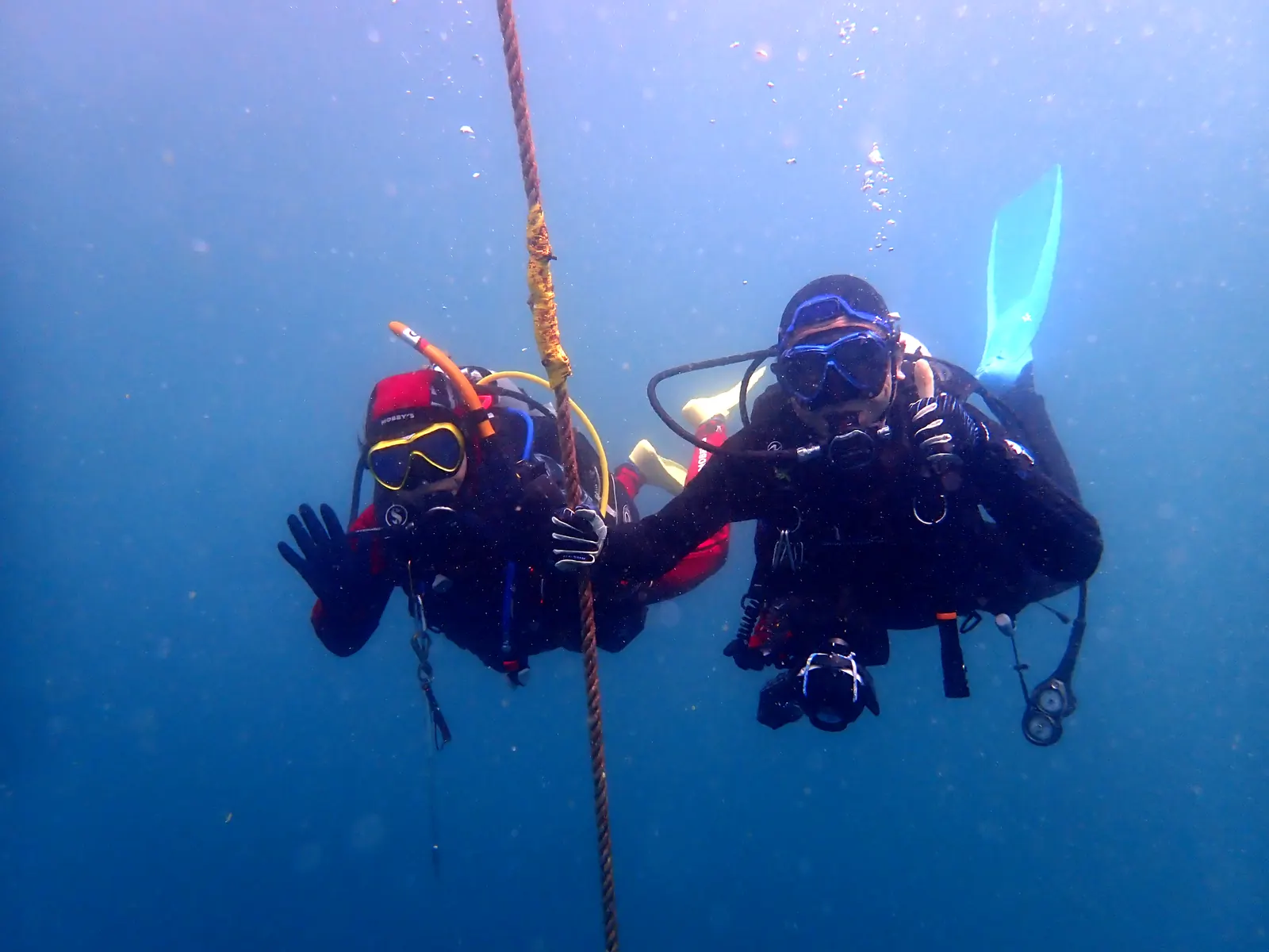 宮川湾で、ブイから伸びるロープのそばで手を振る2人のダイバー