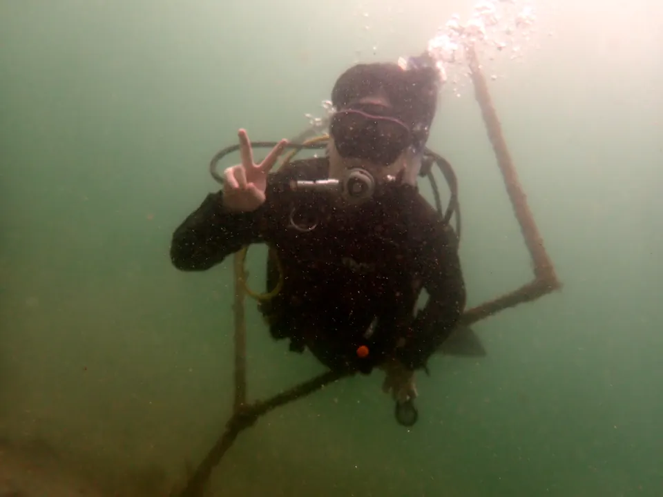 海の中で落ち着いてピースサインをする、講習中のダイバー